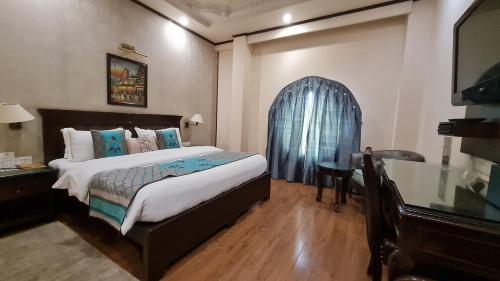 a bedroom with a bed and a table and a window at Hotel Diplomat Residency in New Delhi