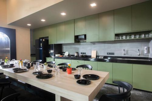 a long table in a kitchen with green cabinets at Mayura Aureole CoLiving in Mumbai