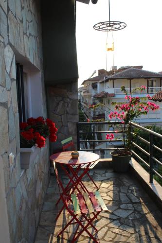 a table and chair on a balcony with flowers at Virginia Rooms in Olympiaki Akti