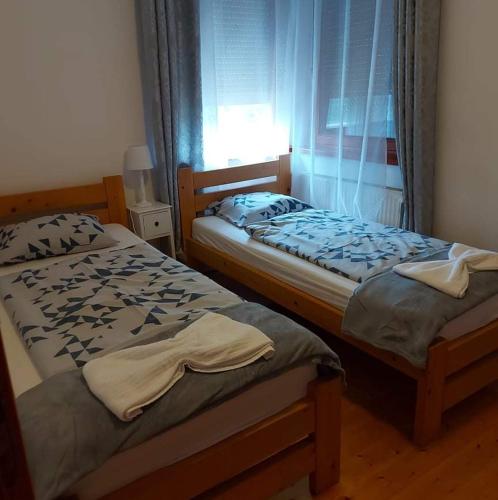 two twin beds in a room with a window at Rege apartman 2 in Alsóörs