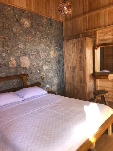 a bedroom with a bed and a stone wall at Kabak Ütopya Kamp in Faralya