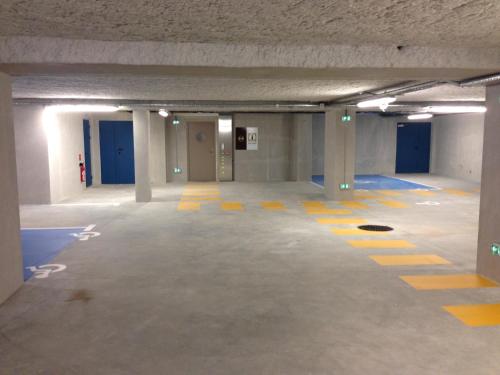 an empty parking garage with blue doors and yellow lines on the floor at B&B HOTEL Lyon Sud États-Unis in Vénissieux