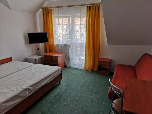 a hotel room with a bed and a chair and a window at JODA Pokoje Goscinne in Rewal