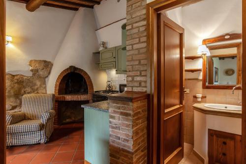 a kitchen with a stone fireplace and a sink at Il Torrino Country Resort in Montaione