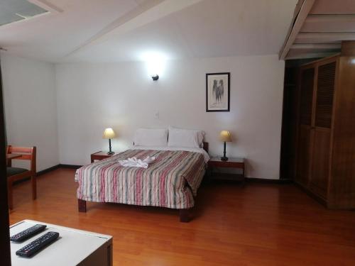 1 dormitorio con 1 cama con 2 mesas y 2 lámparas en Room in Guest room - Amazing Junior Suite Close The Airport And Trade Center, en Bogotá