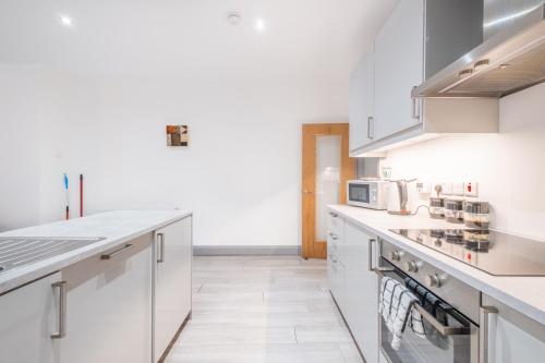 eine weiße Küche mit weißen Schränken und Geräten in der Unterkunft Portrush Marine Apartments flat 3 in Portrush