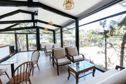 um quarto com janelas, cadeiras e mesas em Minh Chi Hotel em Da Lat