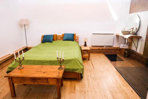 Un dormitorio con una cama verde y una mesa en La Maison du Saula en Lafrançaise