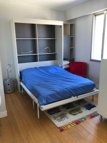 um quarto com uma cama com um cobertor azul em Studio vue mer em Beaulieu-sur-Mer