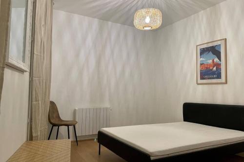 a bedroom with a bed and a chair and a chandelier at République :Appartement T3 Centre historique in Perpignan