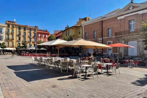 un patio extérieur avec tables, chaises et parasols dans l'établissement République Appartements Centre historique, à Perpignan
