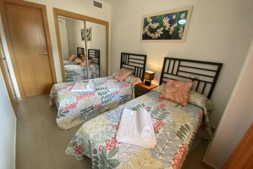 Apartamento Playa Marina Particular Isla Canela في هويلفا: غرفة نوم بسريرين ومرآة