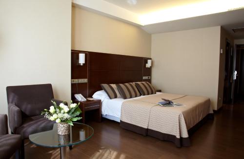 Habitación de hotel con cama, silla y mesa en Hotel Coia de Vigo, en Vigo
