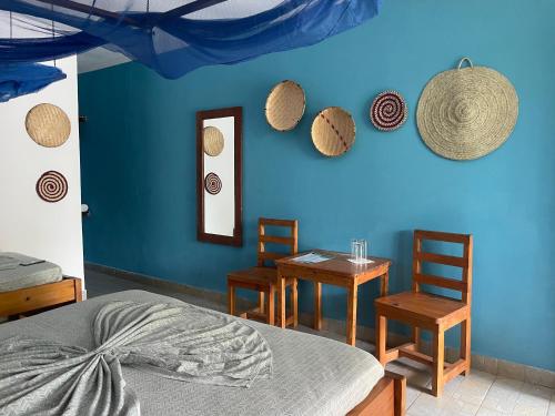 a bedroom with a blue wall with two tables and chairs at Highland Bungalows in Nungwi