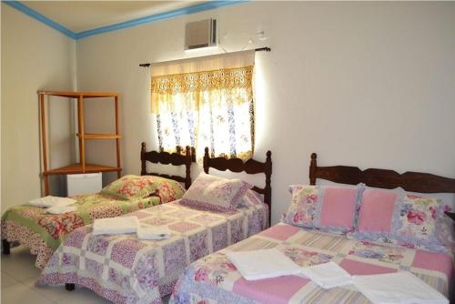 a bedroom with two beds and a window at Pousada Miosotis in Nova Viçosa