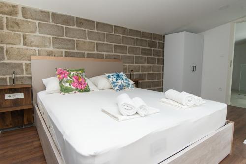 a large white bed in a room with a brick wall at Exclusive Villa Almissa with swimming pool and sea view in Lokva Rogoznica