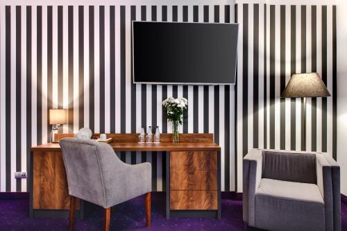 a room with a desk with a television on a striped wall at Best Western Plus Hotel Olsztyn Old Town in Olsztyn