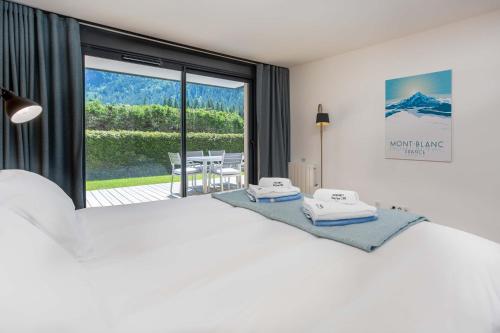 1 dormitorio con 1 cama blanca grande y balcón en La Cordee 703 Apartment - Chamonix All Year, en Chamonix-Mont-Blanc