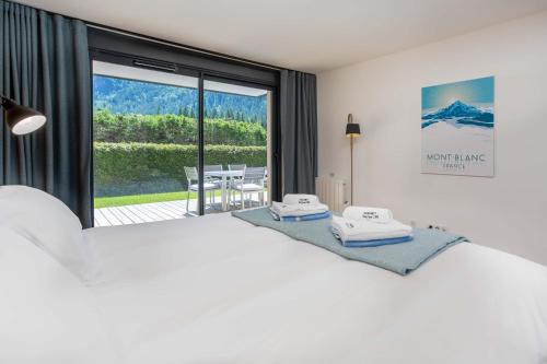 ein Schlafzimmer mit einem großen weißen Bett und einem Balkon in der Unterkunft La Cordee 703 Apartment - Chamonix All Year in Chamonix-Mont-Blanc