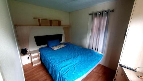 a small bedroom with a blue bed and a window at Domek holenderski święty spokój Bieszczady in Ropienka