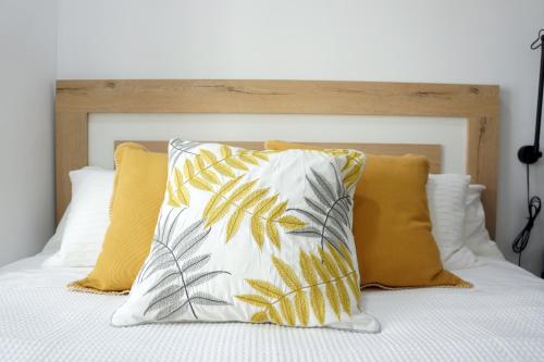 a bed with yellow and white pillows on it at Barcelona COZY Apartment in Hospitalet de Llobregat