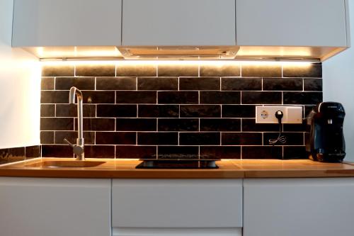 a kitchen with a sink and a black tiled wall at Barcelona COZY Apartment in Hospitalet de Llobregat