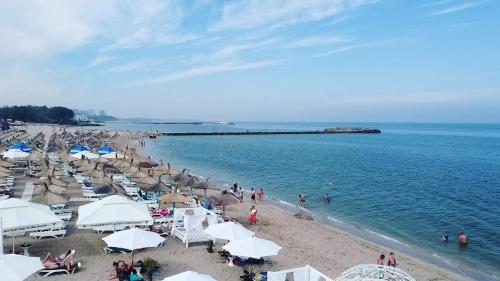 a beach with umbrellas and people on the water at Ery Ville Neptun in Neptun