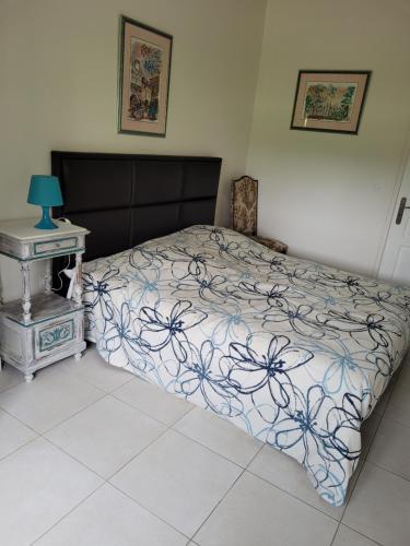 a bedroom with a bed and a nightstand with a bedspread with flowers at UN AIR DE VACANCES in Layrac
