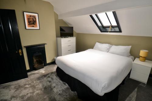 a bedroom with a large white bed and a fireplace at The Wrens in Leeds