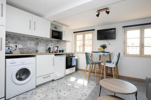 une cuisine avec des appareils blancs et une table avec des chaises dans l'établissement Appartement climatisé - Bleu Azur - hyper-centre de Toulon, à Toulon