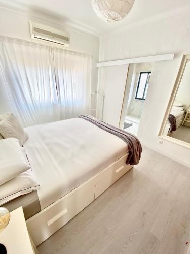 a white bedroom with a large bed and a mirror at Vivenda Sossego do Mar in Ferragudo