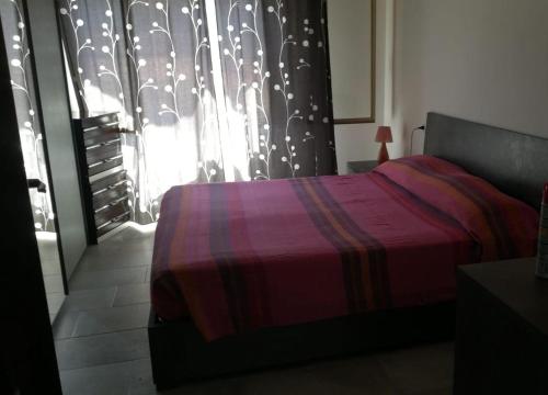 a bedroom with a bed and a window with a curtain at Appartamento Monte Argentu in Fluminimaggiore