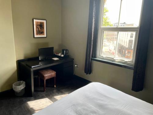 a bedroom with a desk with a laptop and a window at The Wrens in Leeds