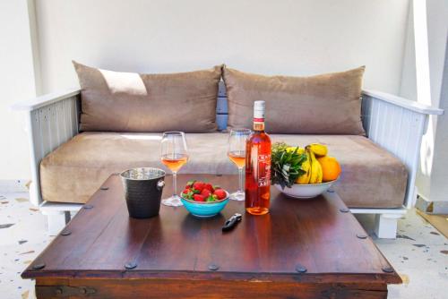 a table with two glasses of wine and fruit on a couch at Tessera Villas & Studios Collection in Gouvia