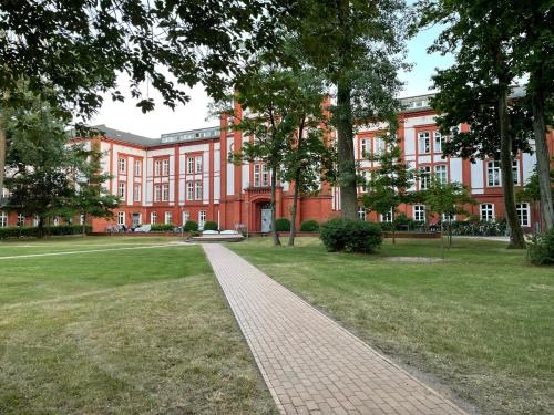 ein großes rotes Gebäude mit einem Backsteinweg davor in der Unterkunft Schlosspark Residenz in Schwerin