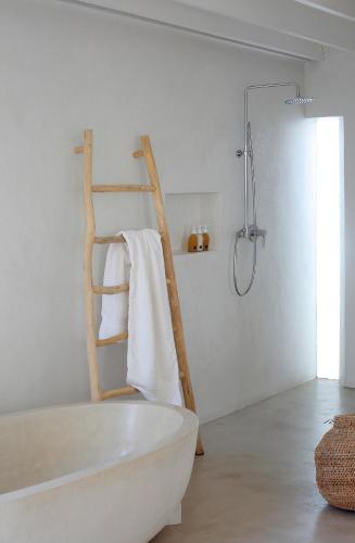 a white bathroom with a bath tub and a towel rack at Strandloper Ocean Boutique Hotel in Paternoster