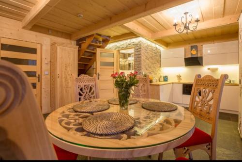 a dining room with a table and chairs and a kitchen at Luksusowe Domki Elizy Luxury Chalets Poronin in Suche