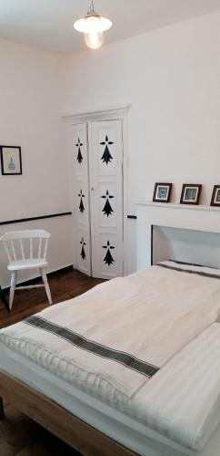 a white bedroom with a bed and a chair at Le Derrien in La Roche-Derrien