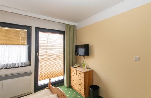 a room with a bed and a tv and a window at Spreewaldhotel Garni Raddusch in Vetschau
