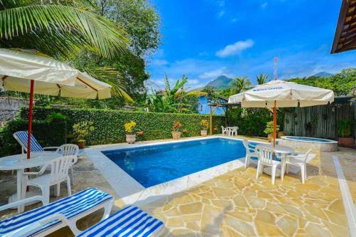 a swimming pool with chairs and umbrellas and a table and chairs at VELINN Pousada Villa Caiçara in Ilhabela