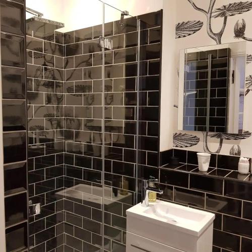 a black tiled bathroom with a sink and a mirror at The Mill France- Near Millau in Saint-Georges-de-Luzençon