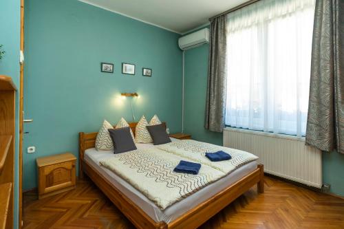 a bedroom with a bed with blue walls and a window at Cecey Vendégház in Eger
