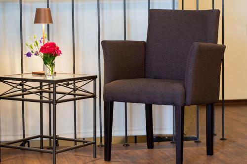 a chair and a side table with a vase of flowers at Hotel MeerLand Pellworm in Pellworm