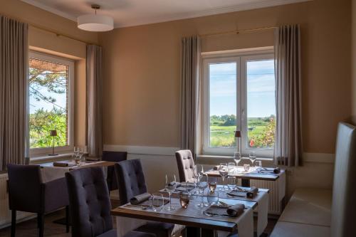 a dining room with tables and chairs and windows at Hotel MeerLand Pellworm in Pellworm