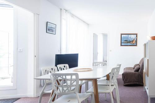 a white dining room with a white table and chairs at Résidence Le Crystal Dinard Plage in Dinard