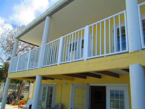 uma varanda numa casa amarela com corrimão branco em Haynes Cay View em San Andrés