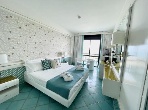 マルゲリータ・ディ・サヴォイアにあるGrand Hotel Termeのベッドとテーブルが備わるホテルルームです。