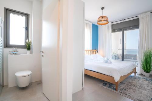 ein weißes Schlafzimmer mit einem Bett und einem Badezimmer in der Unterkunft Beach Apartment in Achziv with Incredible Sea Views by Sea N' Rent in Naharija