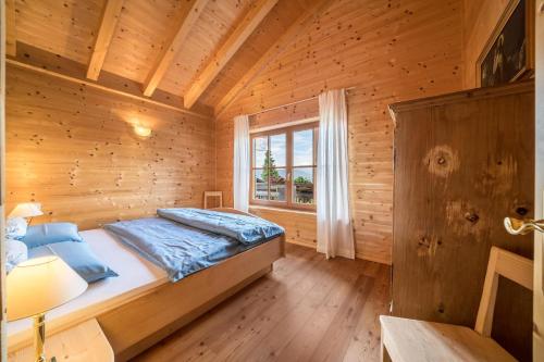 um quarto com uma cama num chalé de madeira em Bergchalet Fuchsberger em Verano