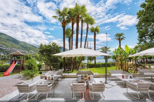 a patio with tables and chairs and a slide at H4 Hotel Arcadia Locarno in Locarno